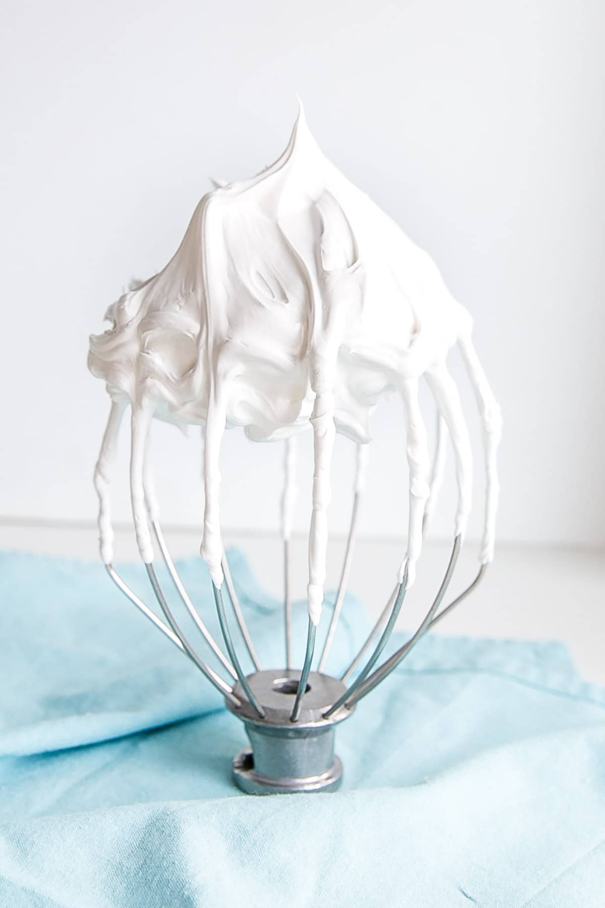This old-fashioned 7 minute frosting recipe is light, delicious, and easy to make. A pure white frosting that's perfect for a variety of delicious desserts. | livforcake.com Meringue frosting on a stand mixer whisk.