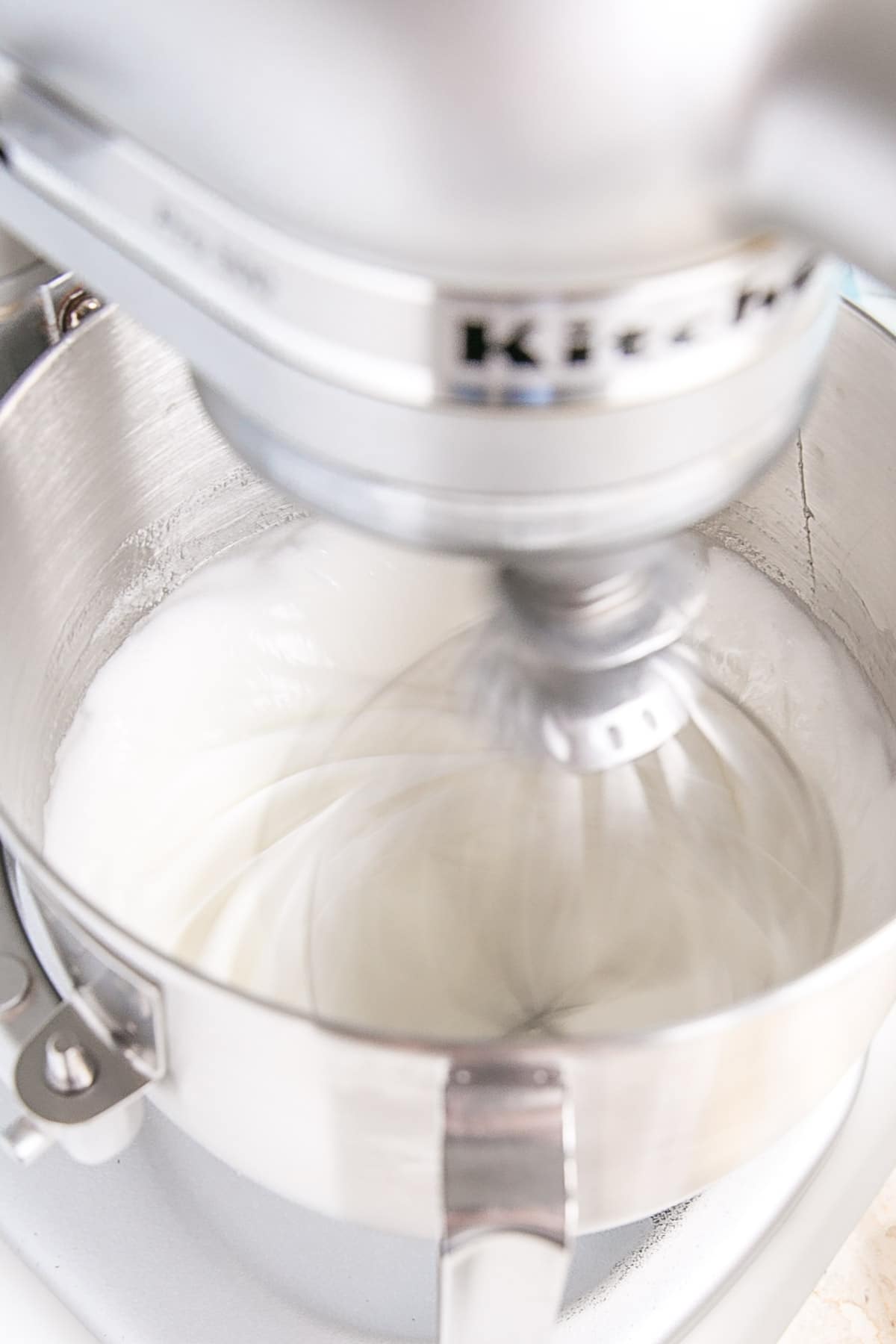 This old-fashioned 7 minute frosting recipe is light, delicious, and easy to make. A pure white frosting that's perfect for a variety of delicious desserts. | livforcake.com The meringue being whipped in the stand mixer.
