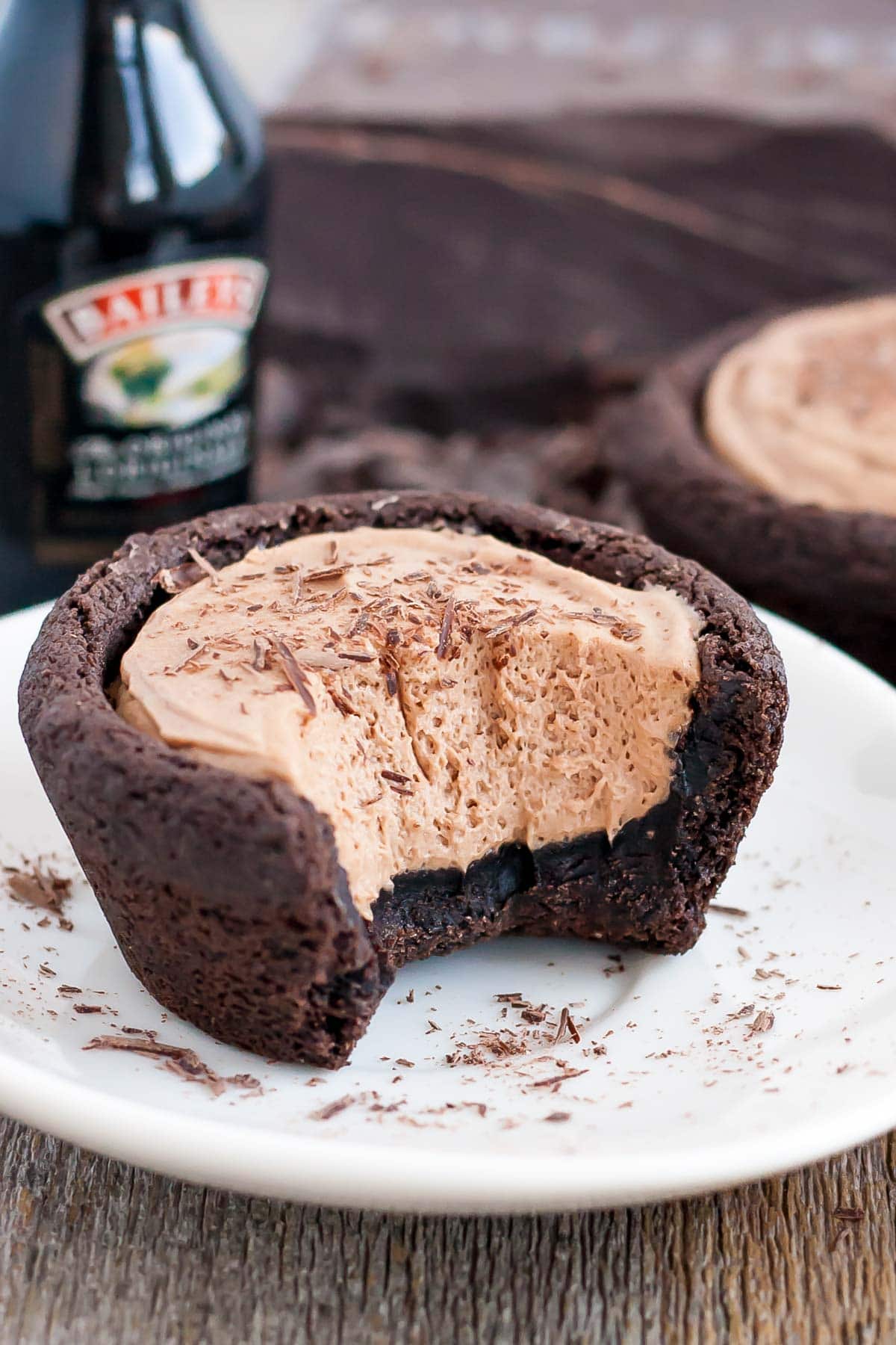 Chocolate cookie cups filled with a chocolate Baileys cheesecake. The perfect bite-sized indulgence! | livforcake.com Baileys cheesecake cookie cup with a bit taken out of it.