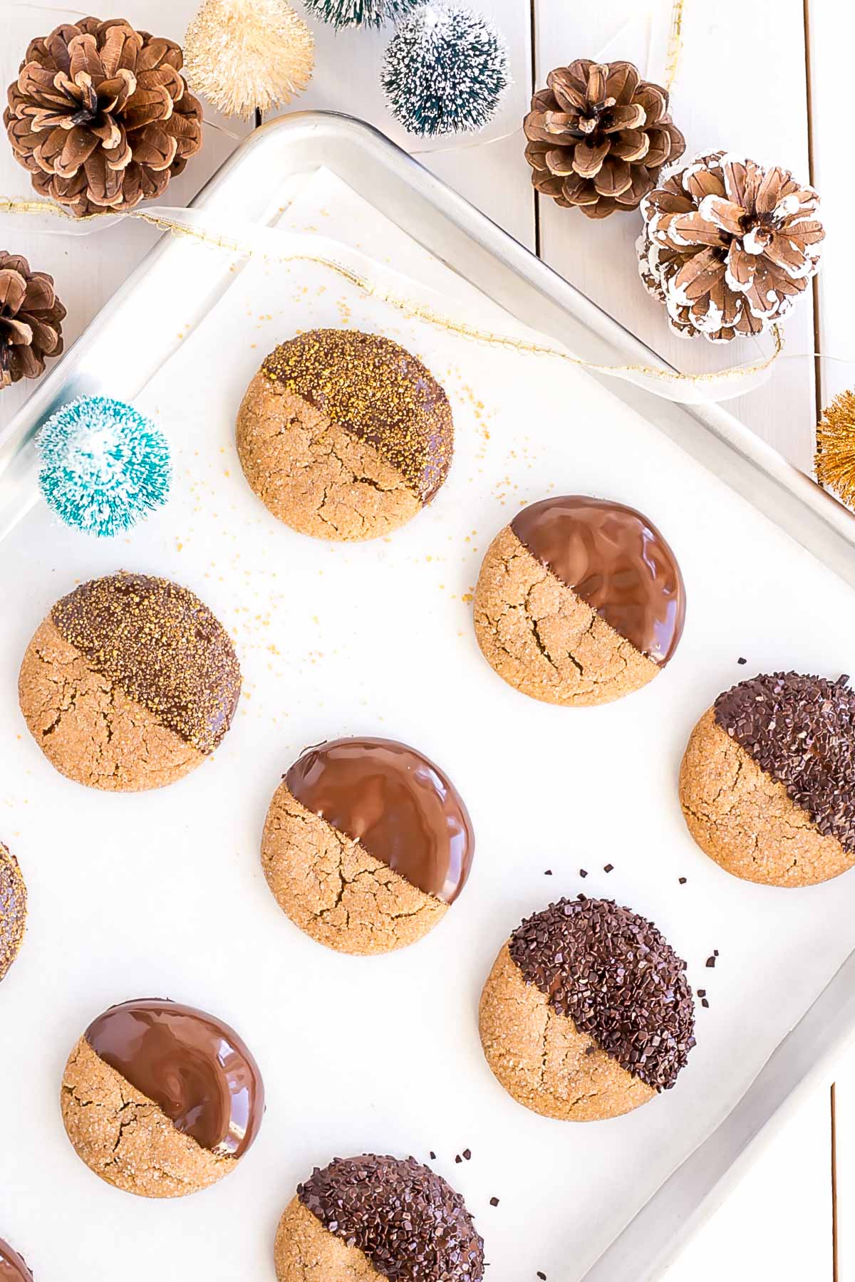 These Chocolate Dipped Gingerbread Cookies are the perfect treat for the holiday season! Chewy ginger spiced cookies dipped in dark chocolate. | livforcake.com Variety of chocolate dipped cookies on a baking sheet.