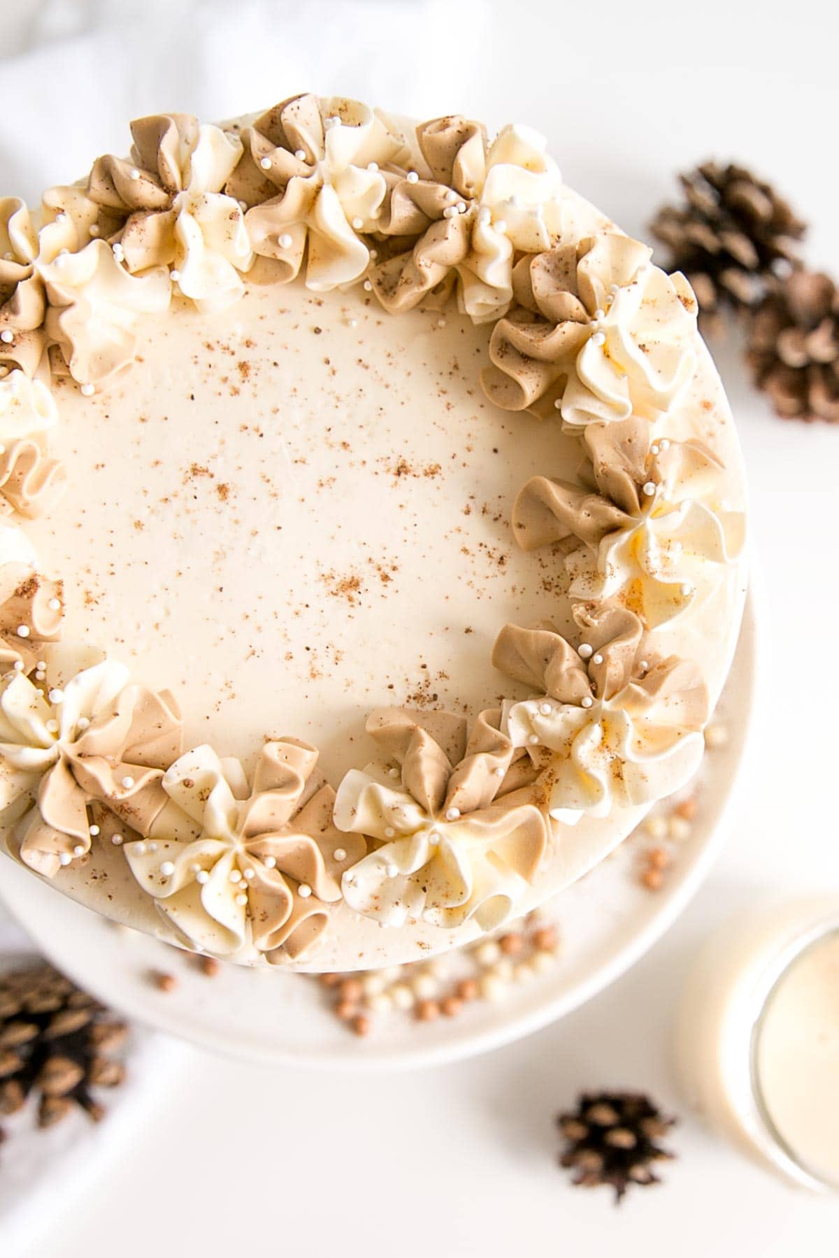 Eggnog Latte Cake! Transform a favourite holiday beverage into a decadent dessert with this Eggnog Latte Cake! Eggnog infused cake layers paired with eggnog and espresso buttercreams. | livforcake.com Overhead shot of cake showing two-tones rosettes on top.