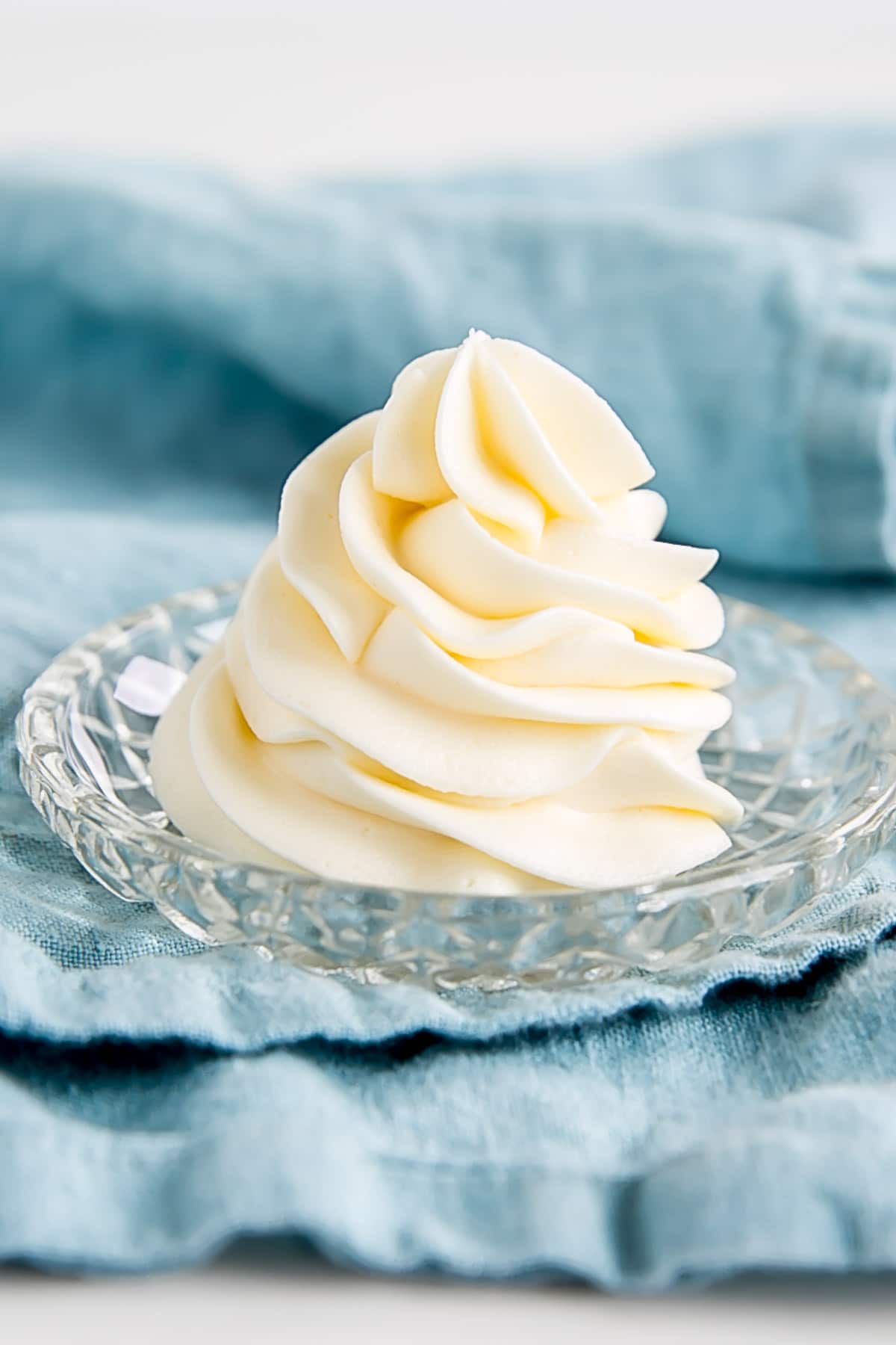 Ermine Frosting (also known as flour buttercream or heritage frosting) is an easy and delicious buttercream made with flour, sugar, milk, and butter. | livforcake.com Piped swirl of Ermine Frosting on a small plate on a blue tea towel.