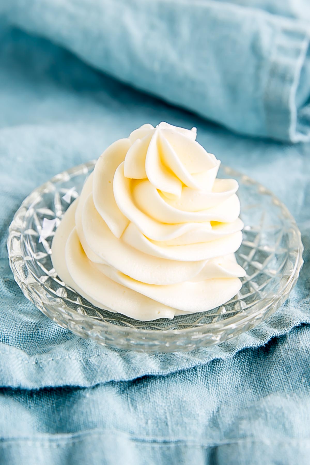 Ermine Frosting (also known as flour buttercream or heritage frosting) is an easy and delicious buttercream made with flour, sugar, milk, and butter. | livforcake.com Angled photo of a piped buttercream swirl on a small glass plate.