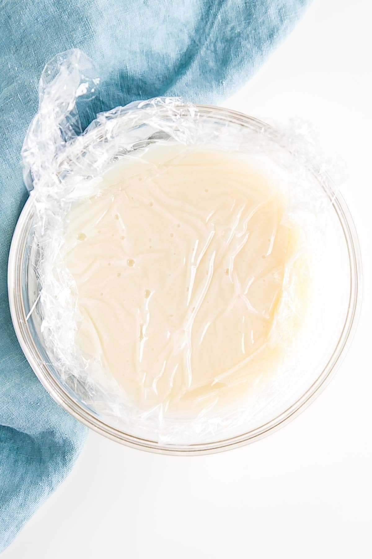 Ermine Frosting (also known as flour buttercream or heritage frosting) is an easy and delicious buttercream made with flour, sugar, milk, and butter. | livforcake.com Flour mixture in a glass bowl with plastic wrap directly on top of it.