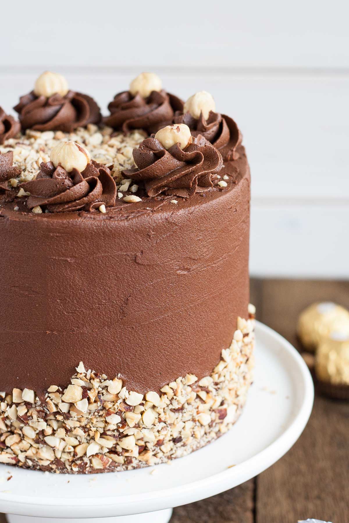 This Ferrero Rocher Cake is your favourite chocolate hazelnut treat in cake form! Chocolate hazelnut cake layers and with a Nutella buttercream. | livforcake.com Close up of rosettes on top of the cake