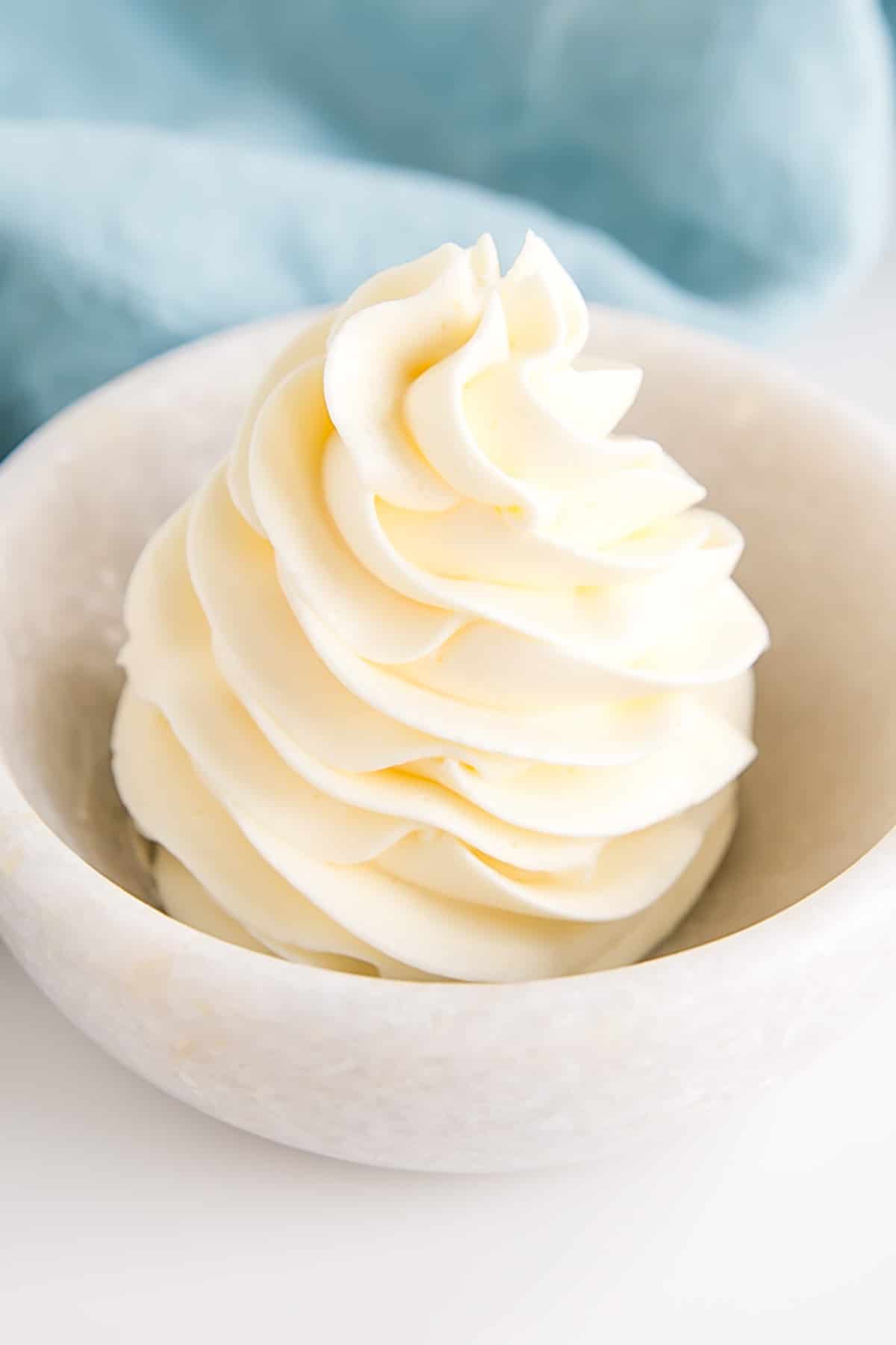 This custard-based German buttercream is made with just a few simple ingredients. Perfect for those who like a rich and silky frosting that isn't too sweet! | livforcake.com German buttercream piped rosette in a small bowl.
