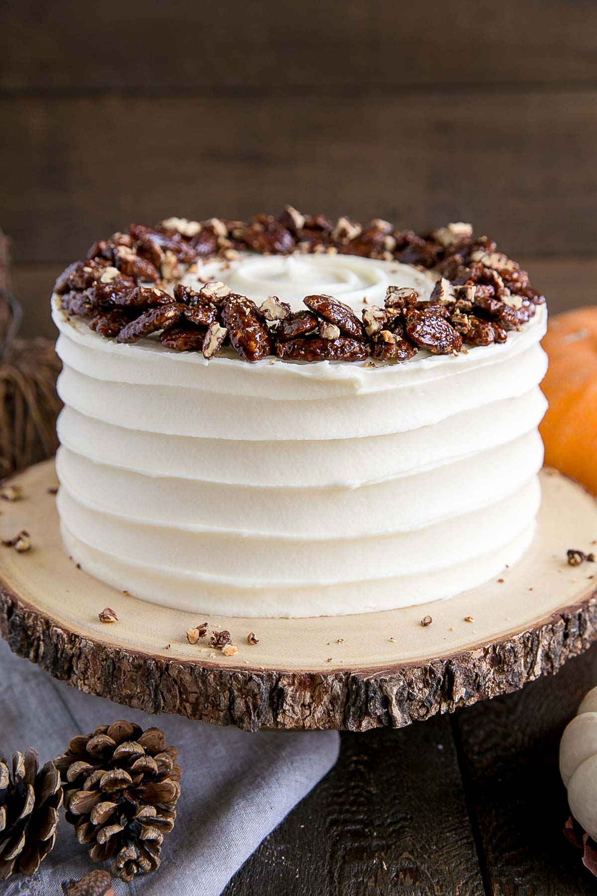 This pumpkin cake is perfect for Fall! Moist and delicious pumpkin cake layers with a tangy cream cheese frosting and crunchy candied pecans. | livforcake.com Glossy candied pecans on top of the cake.