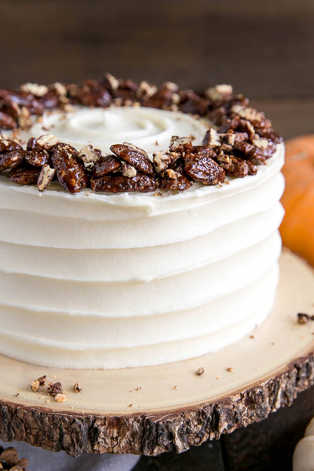 This pumpkin cake is perfect for Fall! Moist and delicious pumpkin cake layers with a tangy cream cheese frosting and crunchy candied pecans. | livforcake.com Close up of the cake with a rustic cream cheese frosting.