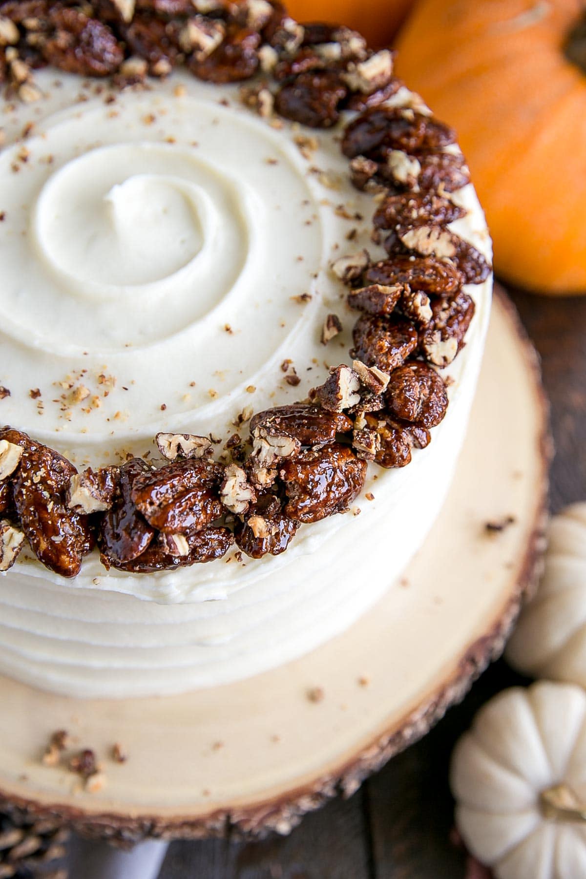 This pumpkin cake is perfect for Fall! Moist and delicious pumpkin cake layers with a tangy cream cheese frosting and crunchy candied pecans. | livforcake.com Overhead shot of candied pecans on top of the cake